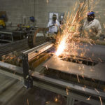 Designers using a plasma cutter for an invention prototype